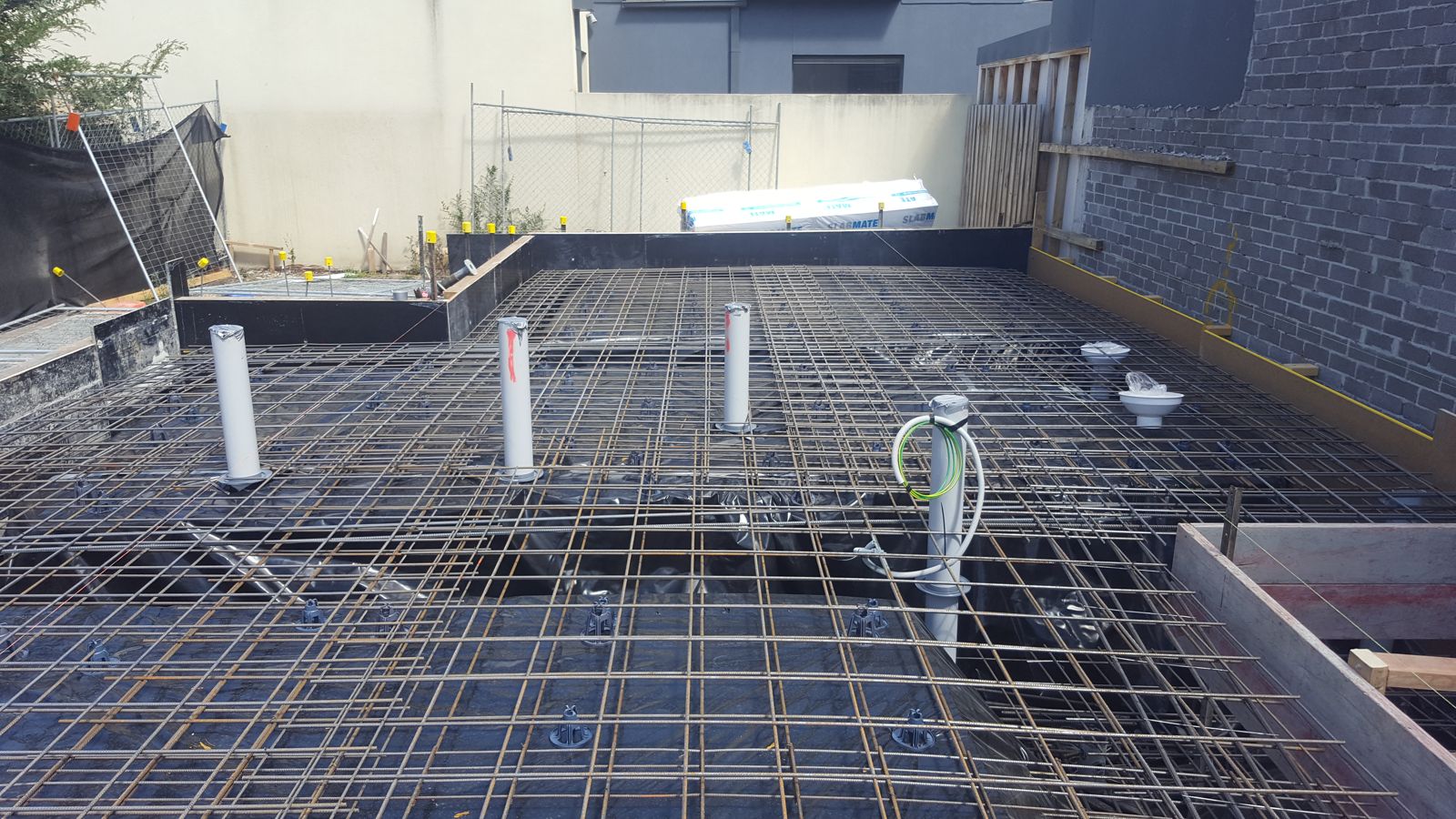 Slab reinforcement with plumbing and electrical services taped and in position before the pour
