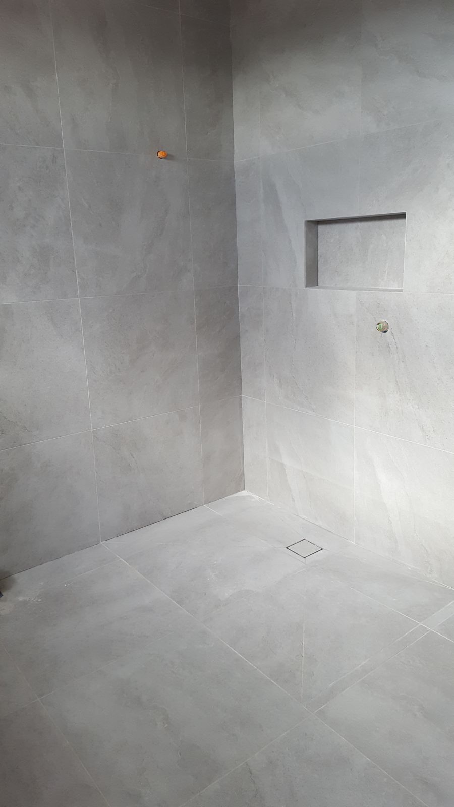 Large-format tiled shower floor with diagonal cuts falling to the centre waste